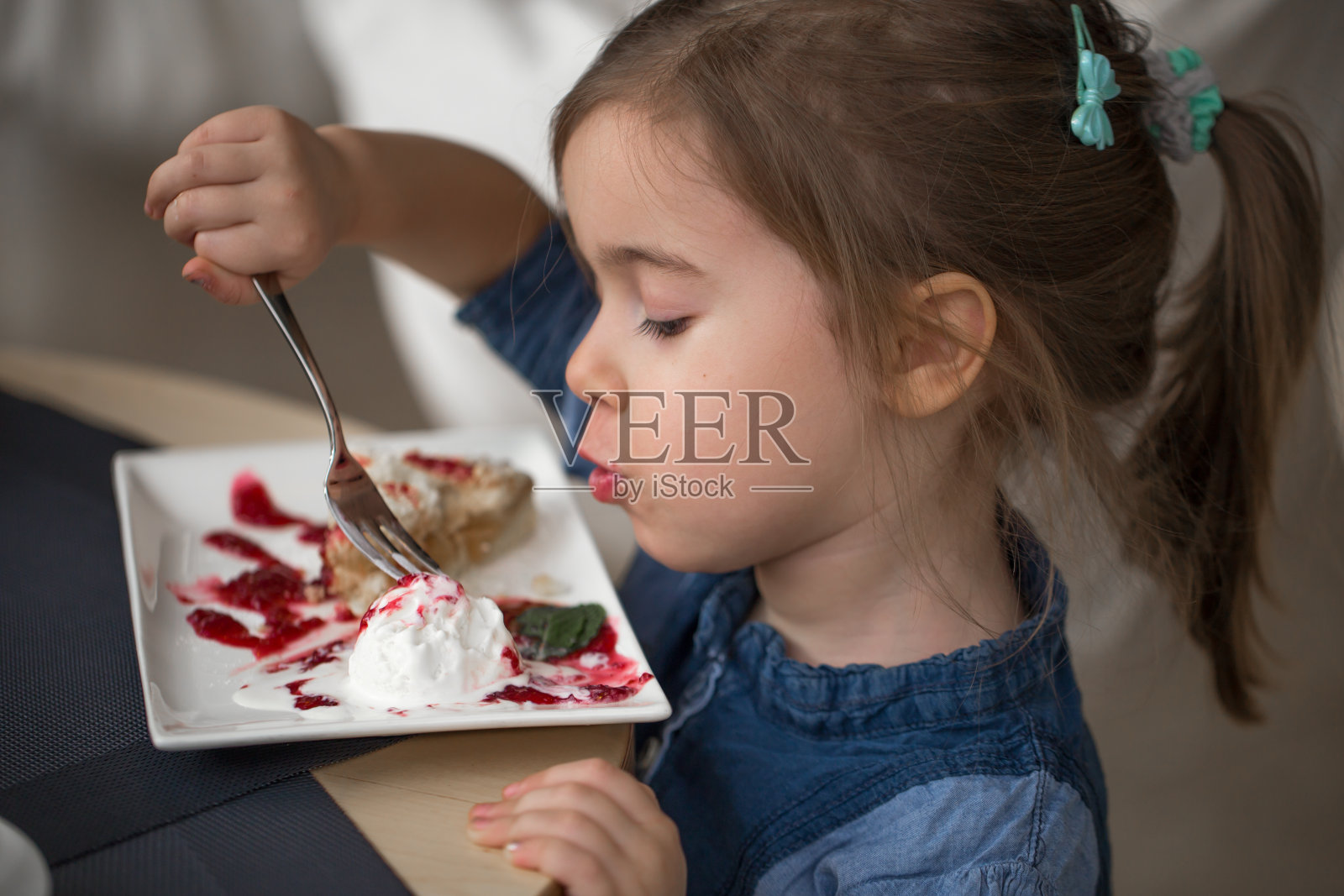 咖啡馆里的小女孩吃着甜点照片摄影图片