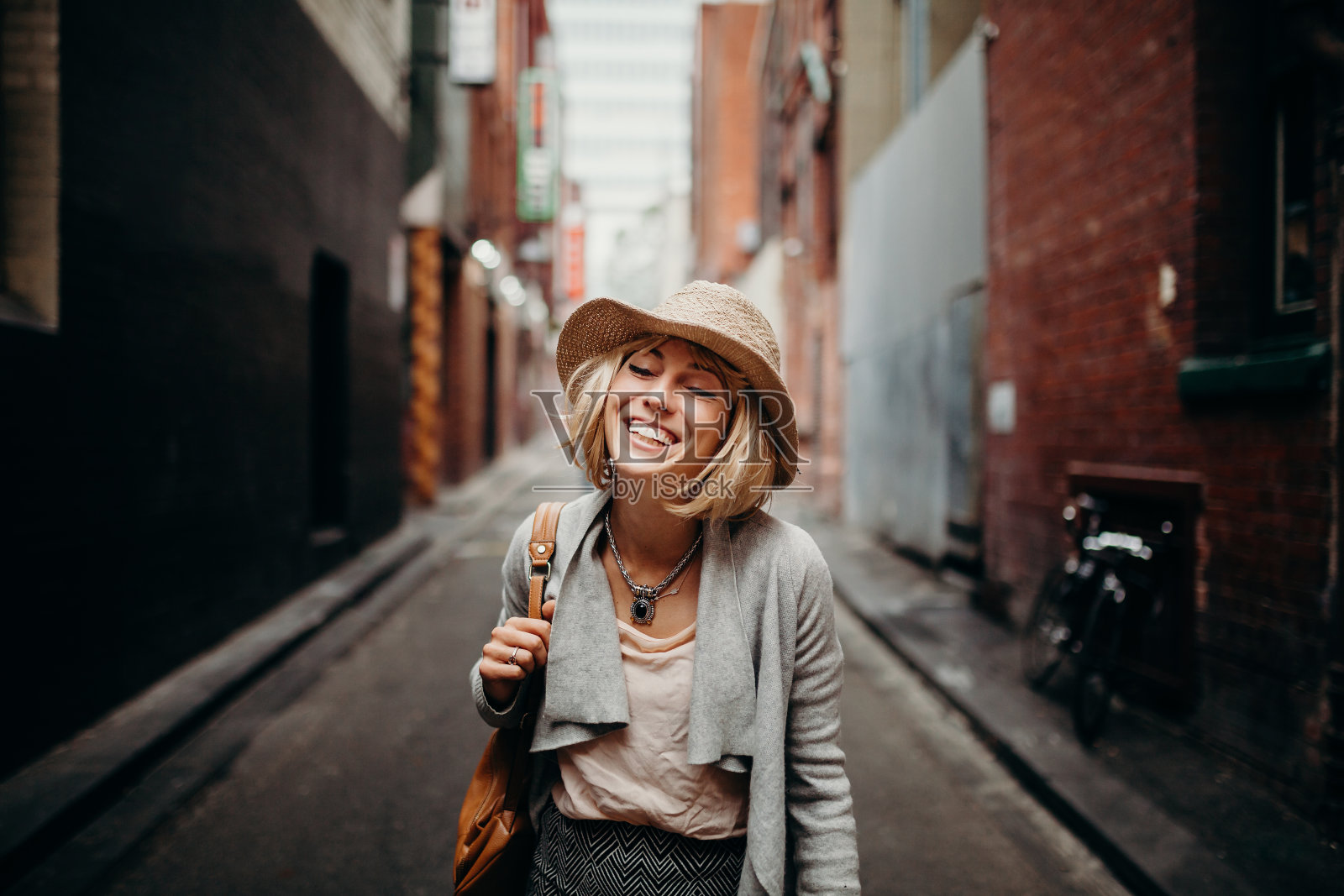 城市生活肖像微笑妇女在一条狭窄的街道中央。照片摄影图片