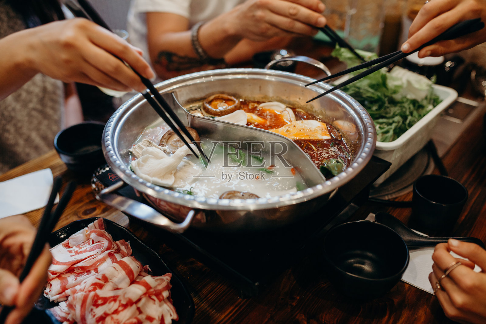 韩式火锅。用筷子夹食物。照片摄影图片