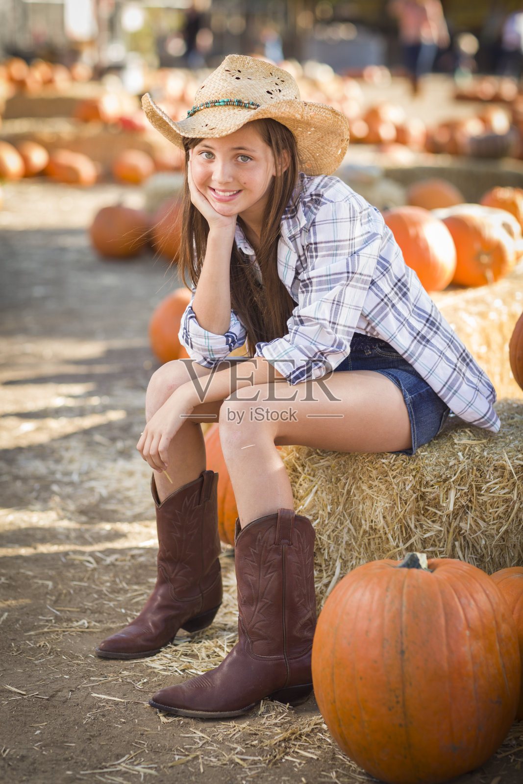 在农场里穿着牛仔帽和靴子的青春期前女孩照片摄影图片