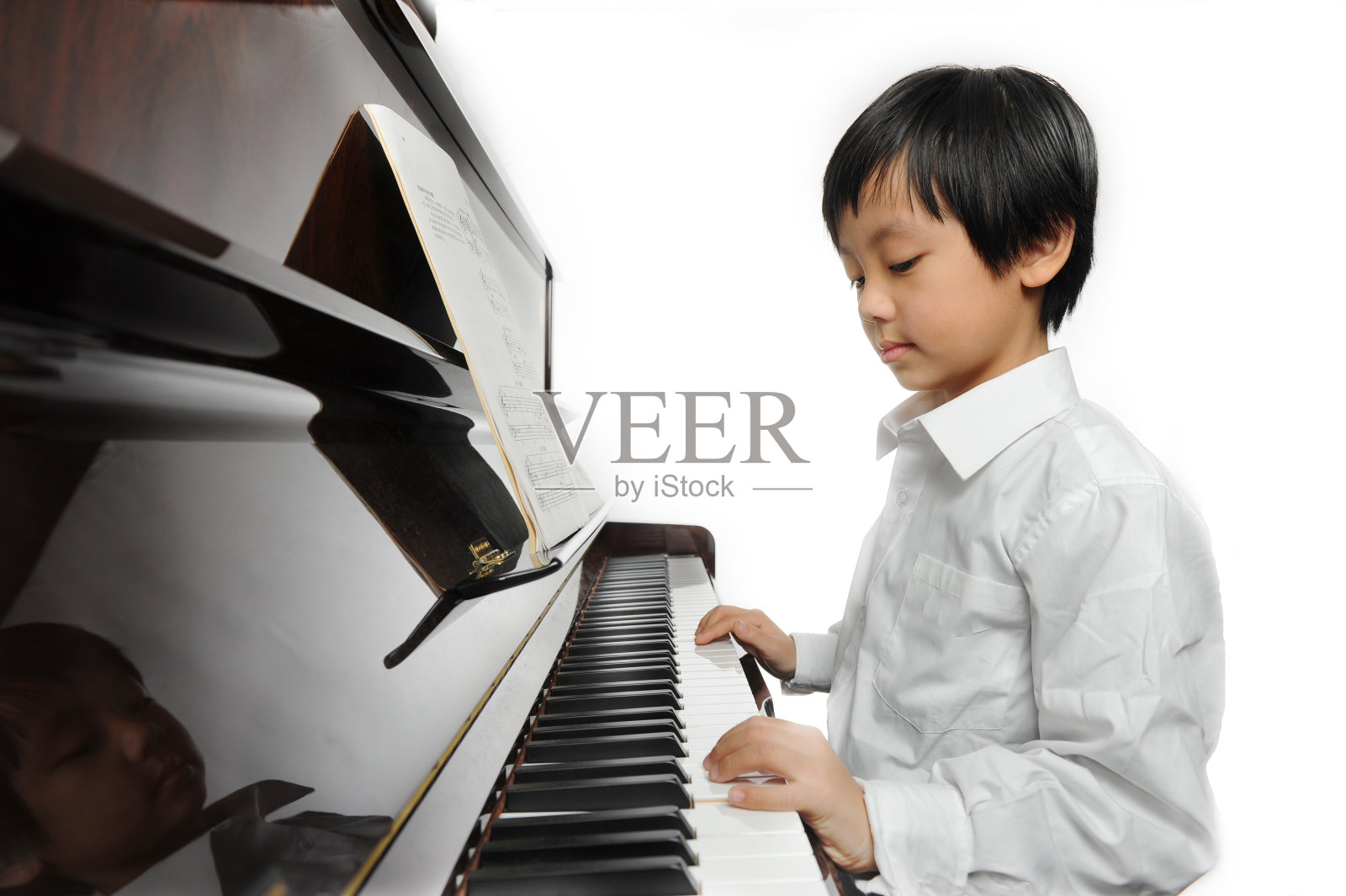 年轻的亚洲男孩在弹钢琴照片摄影图片