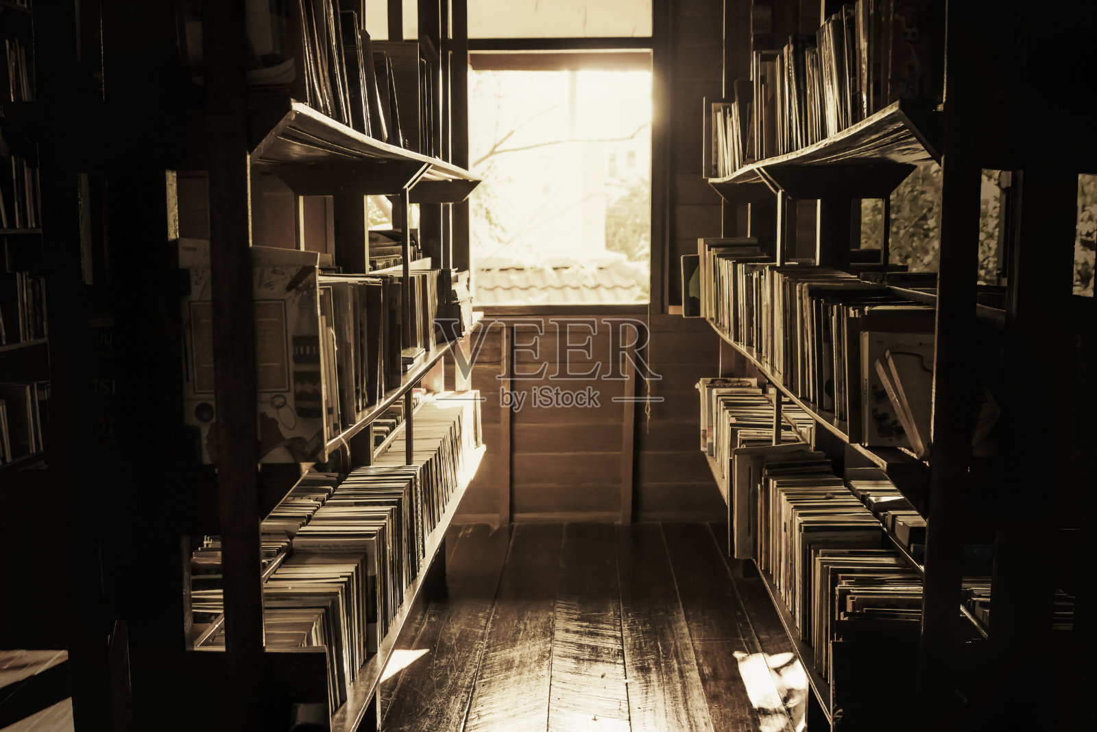 在旧图书馆里，书架上的书凌乱不堪，窗外的灯光闪烁着一种孤寂的气氛，复古的风格。照片摄影图片