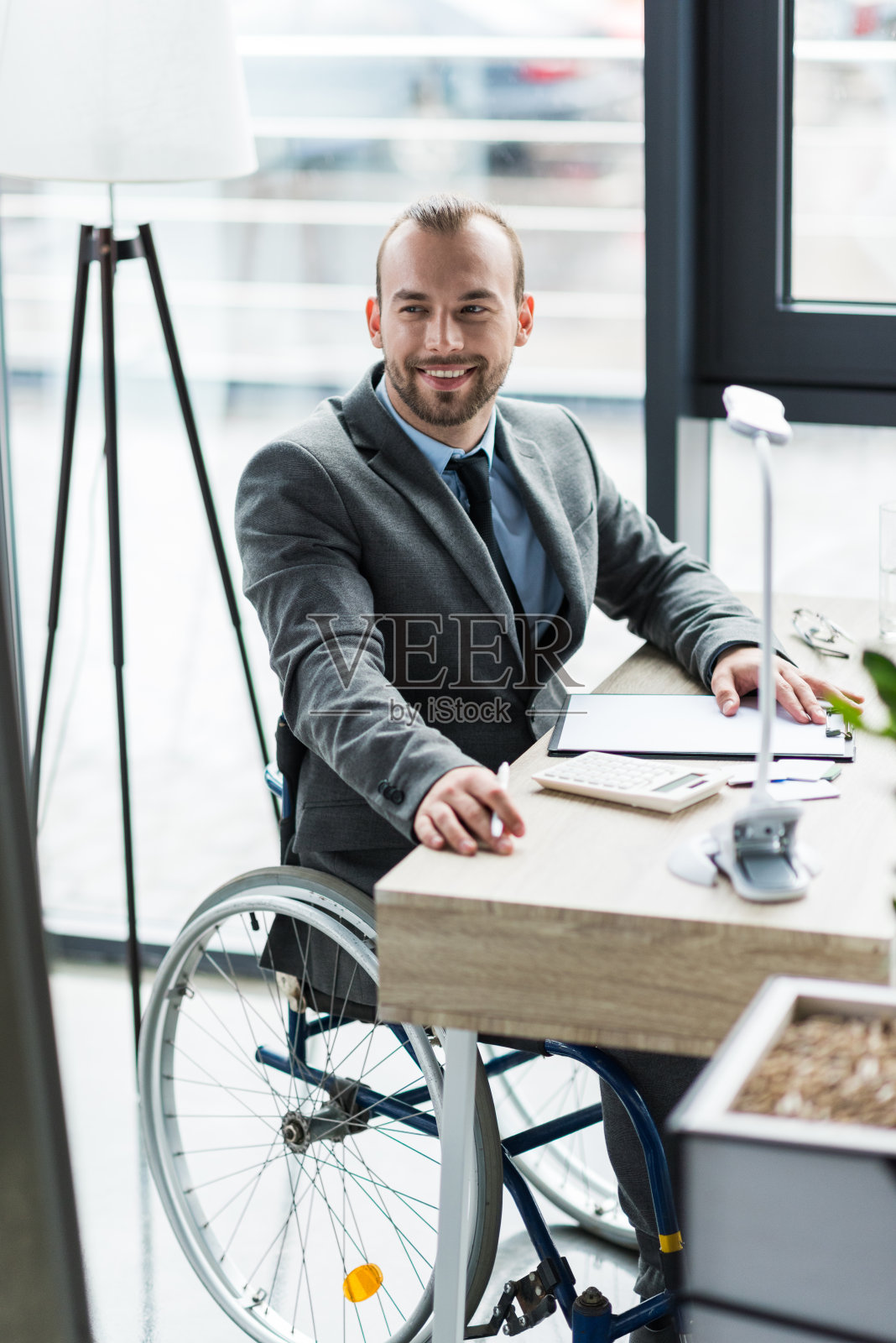 微笑的身体残疾的商人在轮椅上的西装在办公室工作照片摄影图片