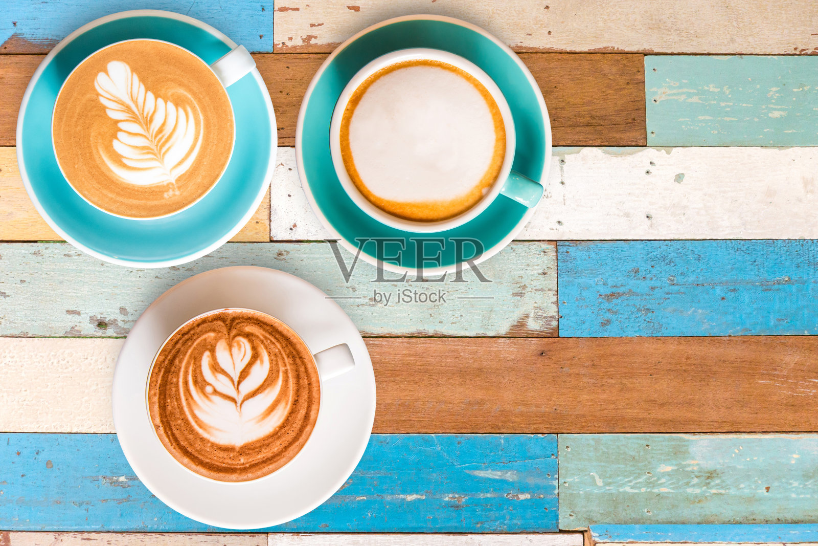 三顶视图热咖啡在杯子和木制桌子上多颜色纹理为背景。照片摄影图片