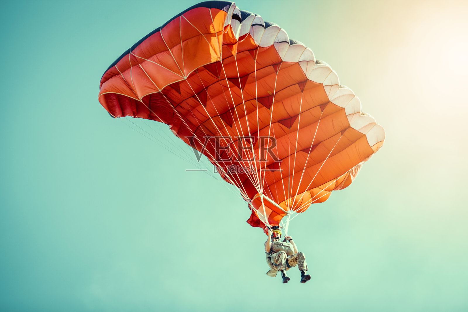 在晴朗晴朗的天空中乘坐彩色降落伞的跳伞者。照片摄影图片