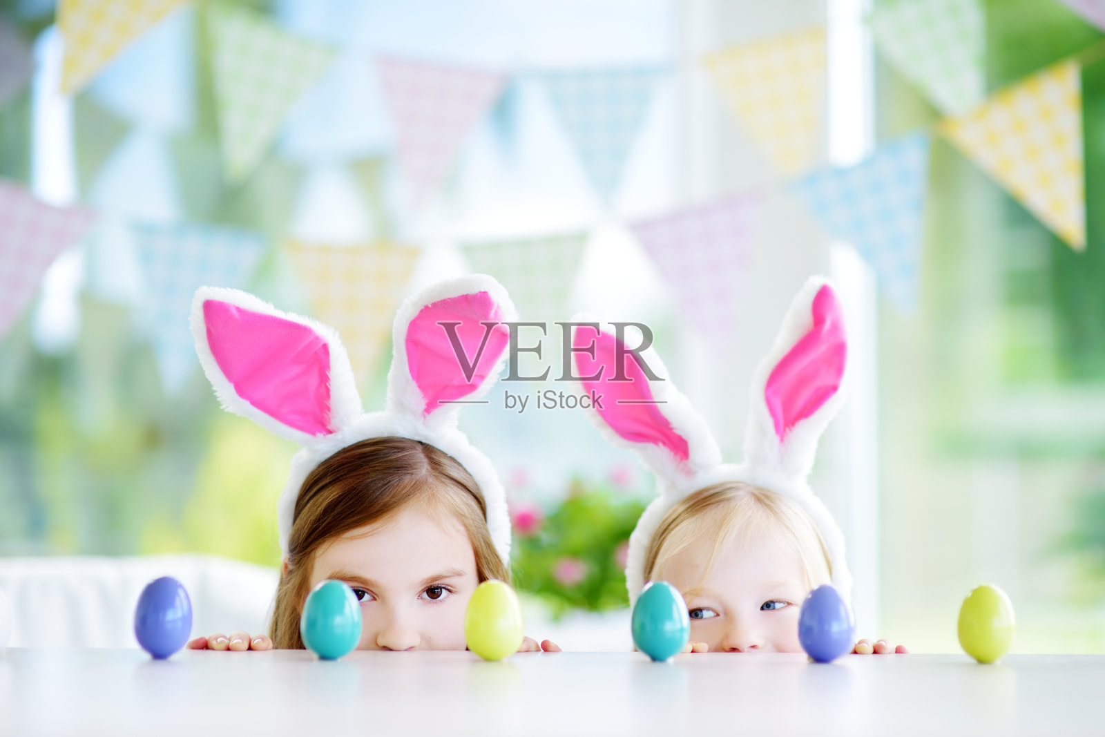 两个可爱的小姐妹戴着兔子耳朵玩找彩蛋游戏照片摄影图片
