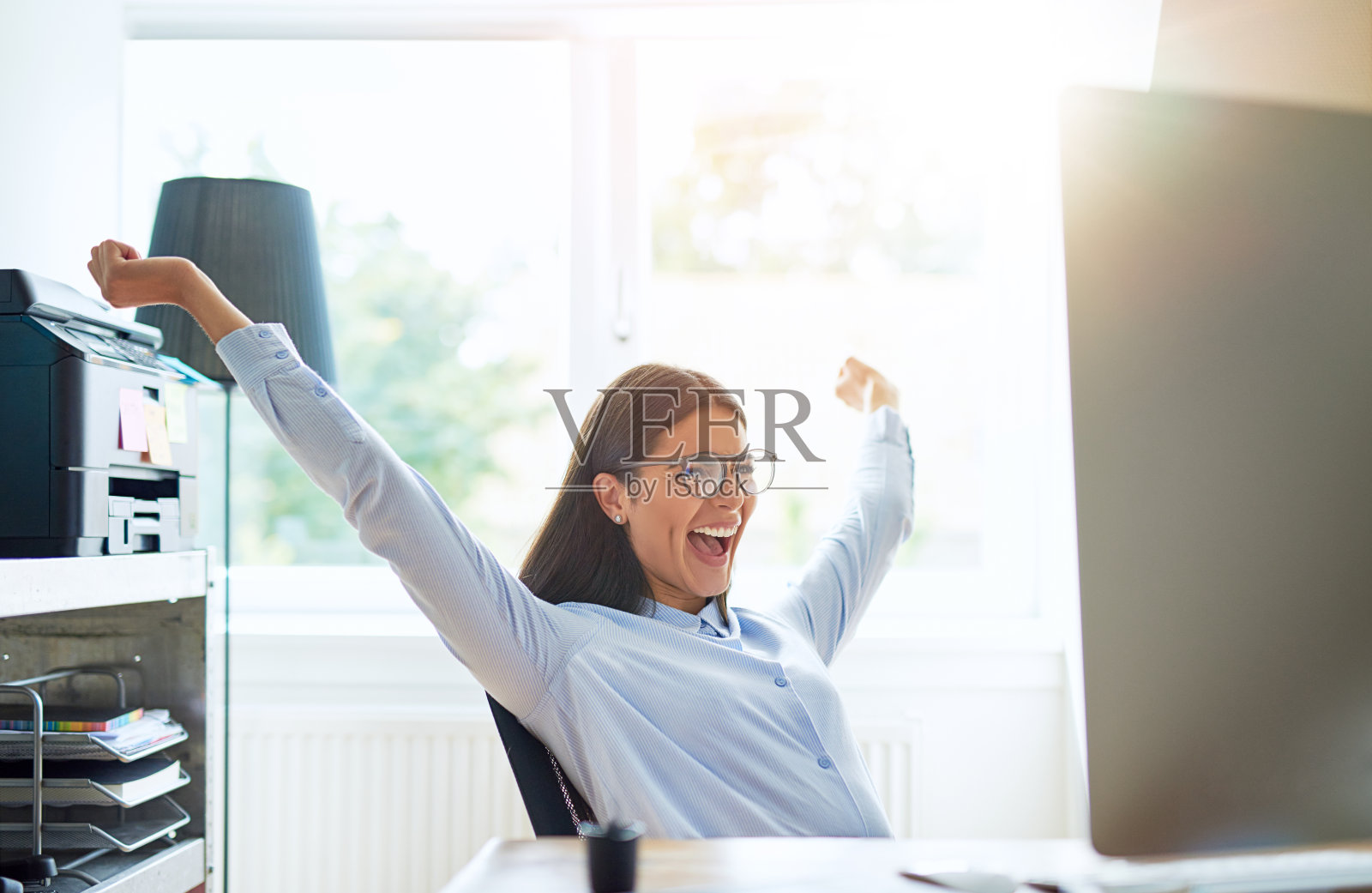 快乐的女人在小办公室里伸开双臂照片摄影图片