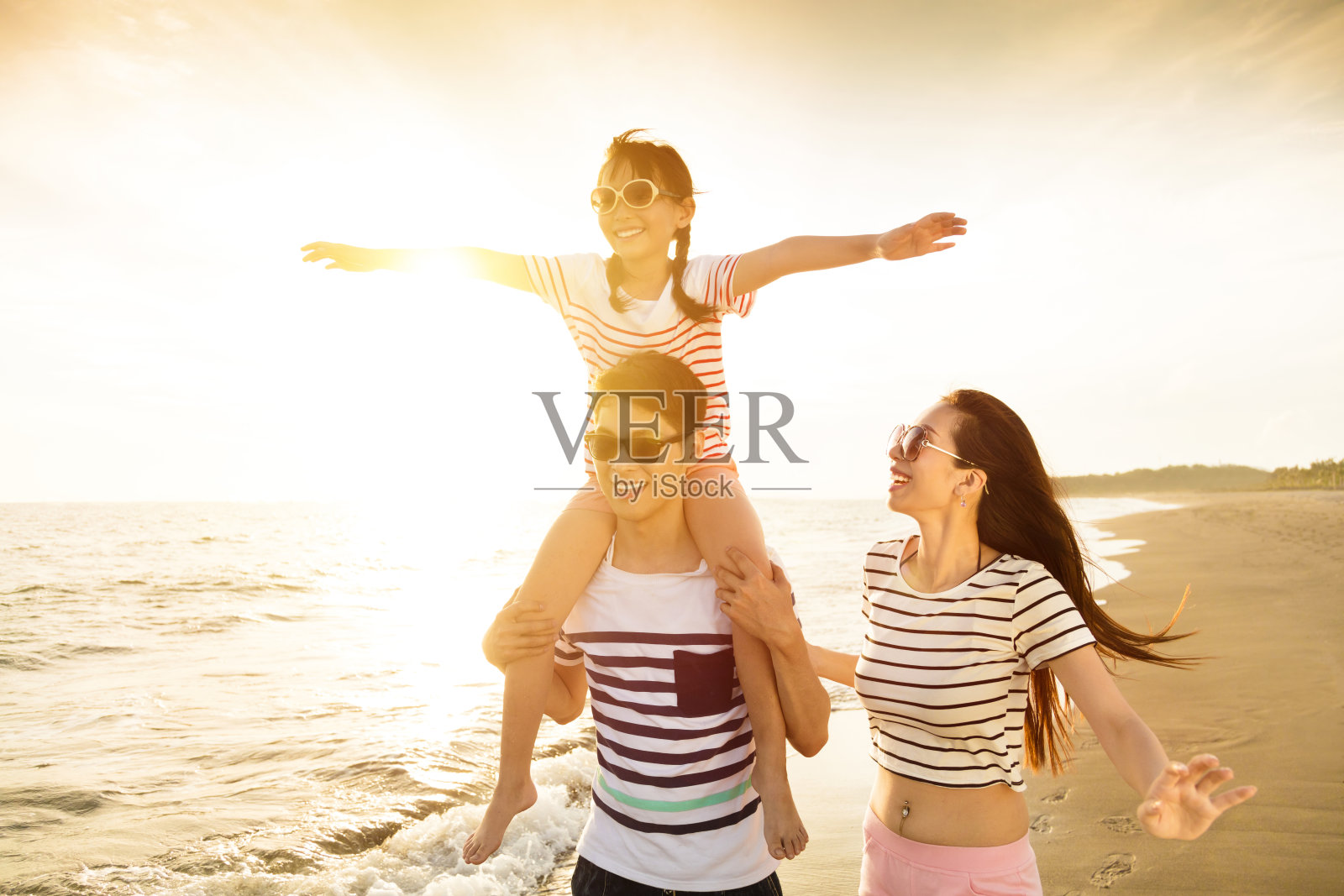 日落时分，幸福的一家人在海滩上玩耍照片摄影图片