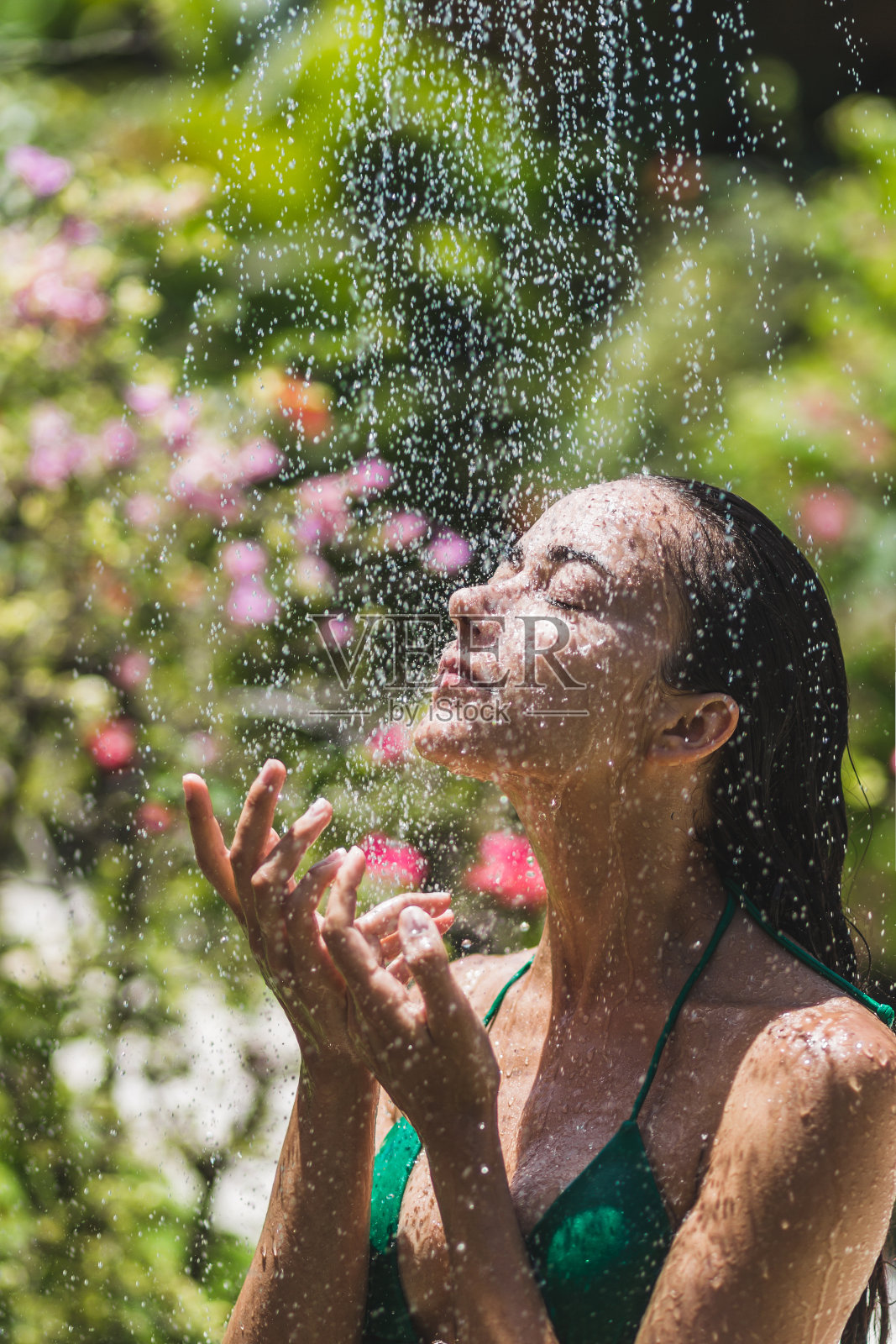 女人洗澡在热带绿色的巴厘岛花园很多花。新鲜的干净的水。豪华水疗中心照片摄影图片