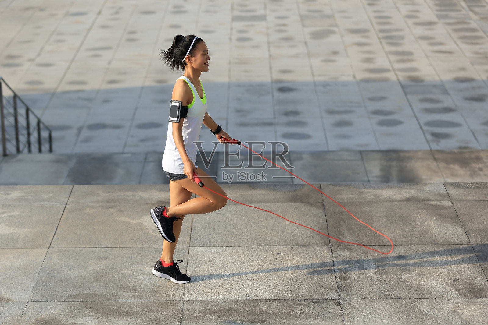 年轻的健身女子在城市跳绳照片摄影图片