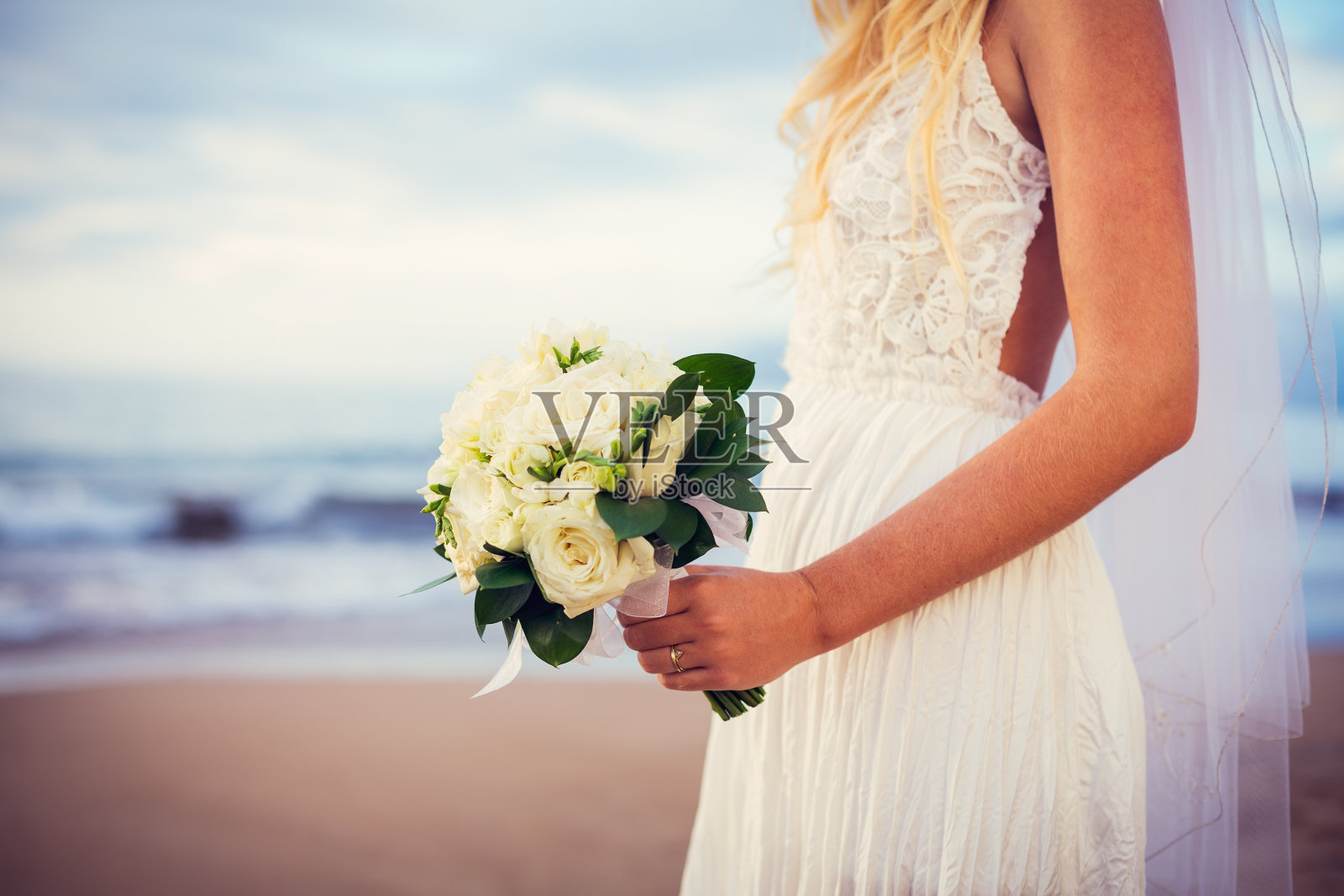 美丽的新娘站在日落的海滩上照片摄影图片