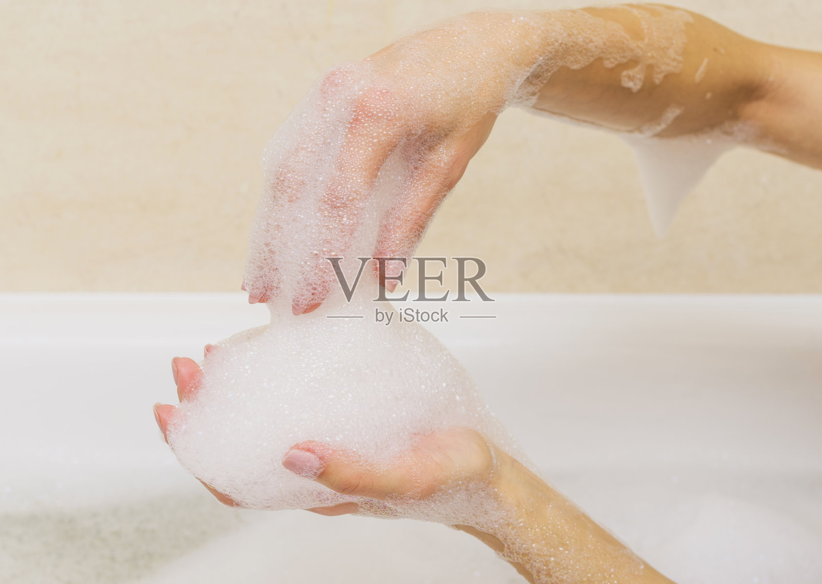 美丽的女性双手在白色肥皂。照片摄影图片
