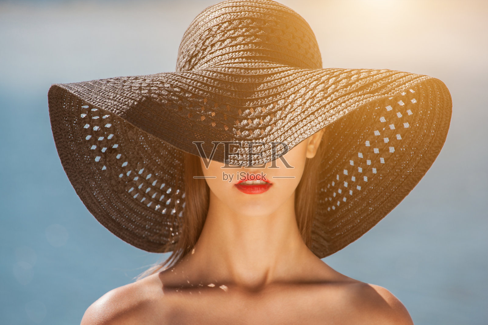 迷人的女孩戴着黑色的帽子，在海滩上照片摄影图片