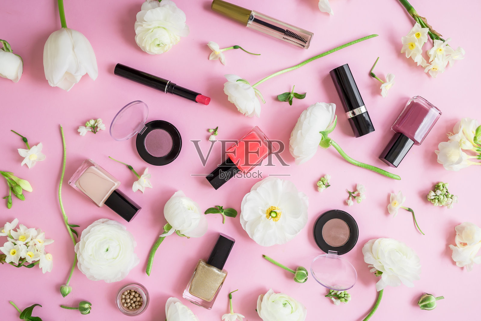 女性的办公桌上有化妆品，口红，指甲油，眼影和白色的花朵孤立在粉红色的背景。平躺，俯视图。照片摄影图片