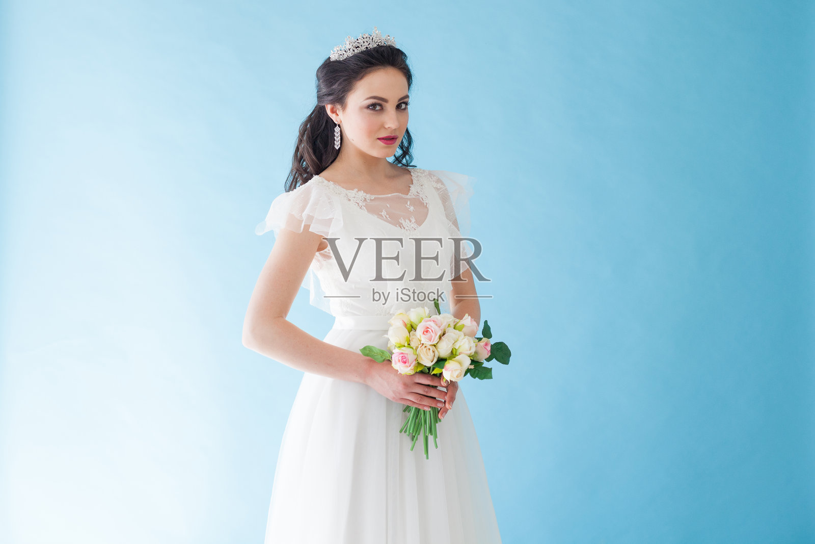 公主新娘在白色的裙子与一个皇冠上的蓝色背景照片摄影图片