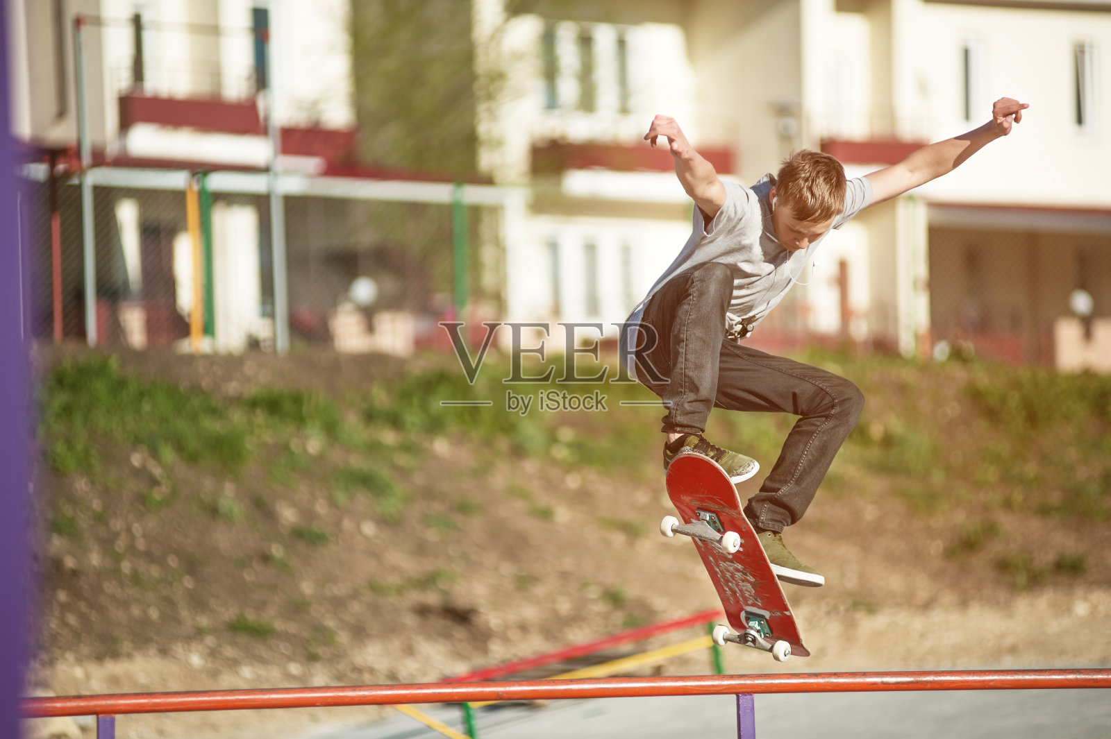 一个十几岁的滑板爱好者在城市郊区的一个滑板公园里玩奥利把戏照片摄影图片