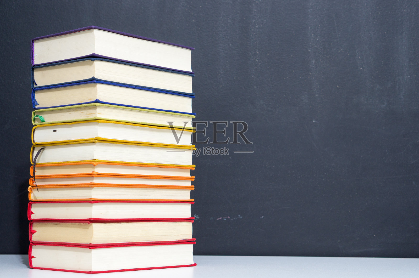 一堆彩色的书在黑板的背景上照片摄影图片