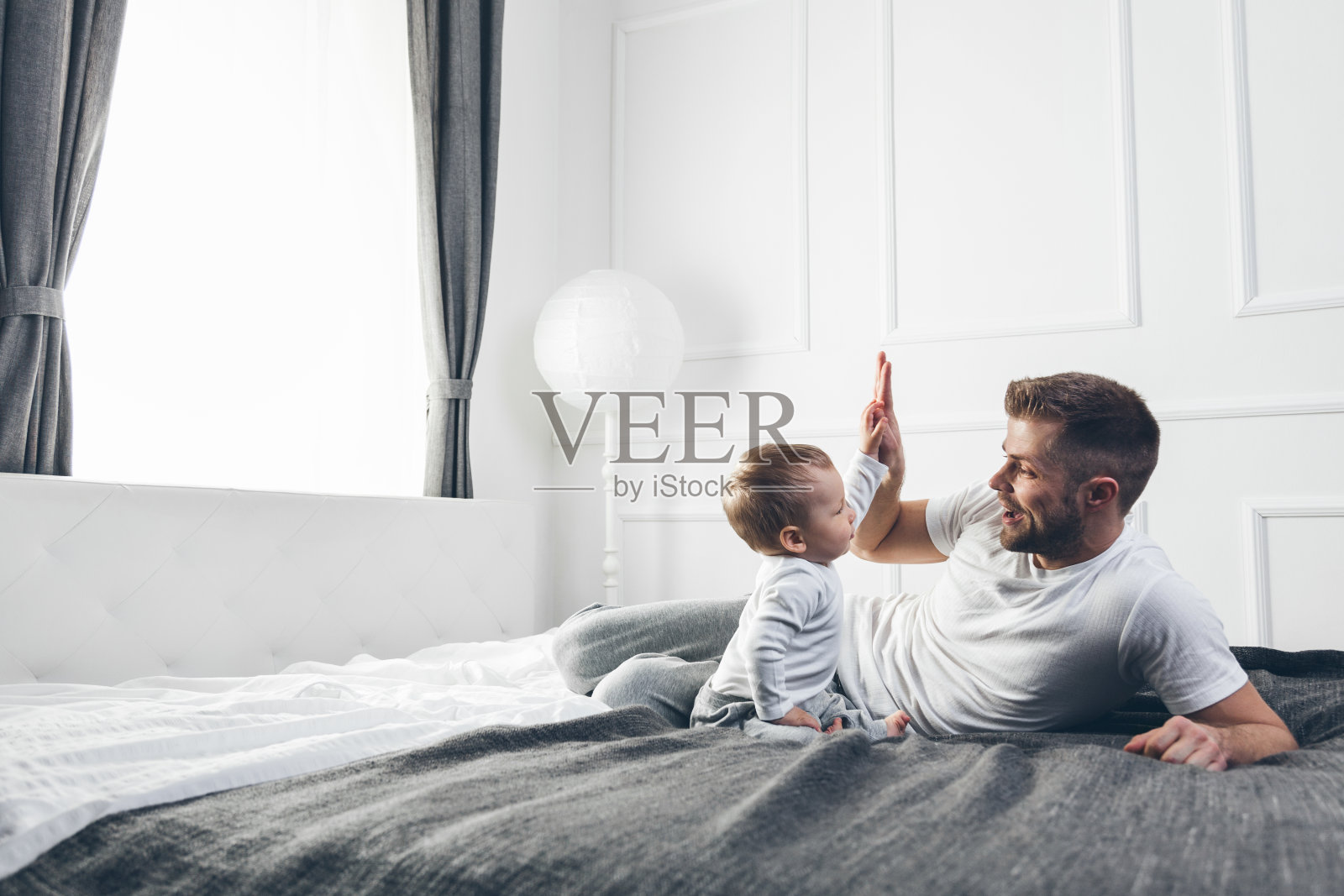 快乐的父亲和他的儿子在家里的床上玩照片摄影图片