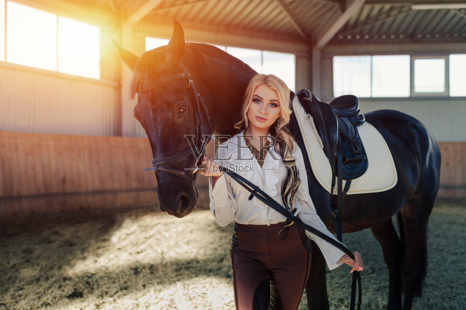 美丽优雅的年轻金发女孩站在她旁边的马穿着制服比赛照片摄影图片