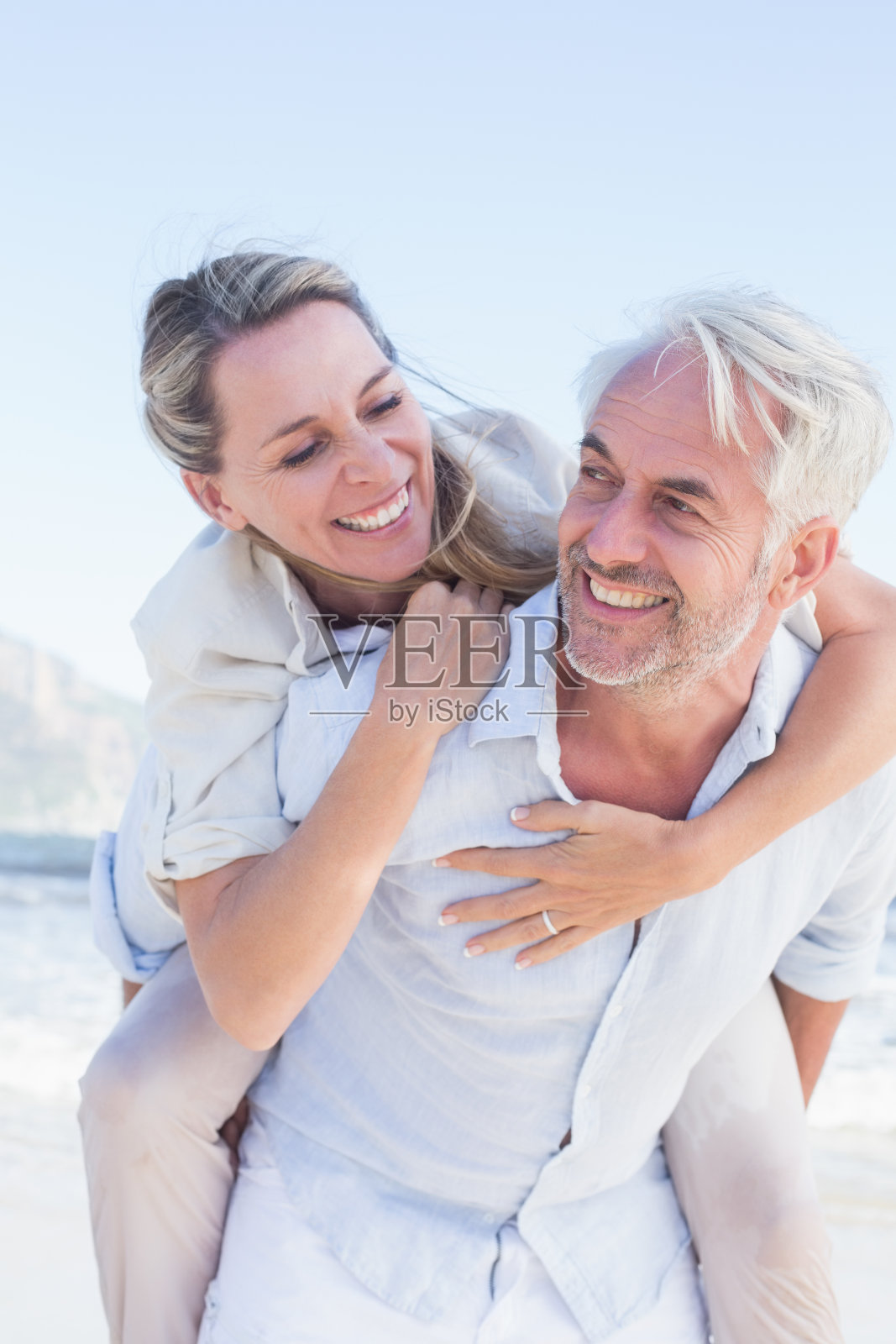 一个男人在海滩上给他微笑的妻子一只小猪照片摄影图片