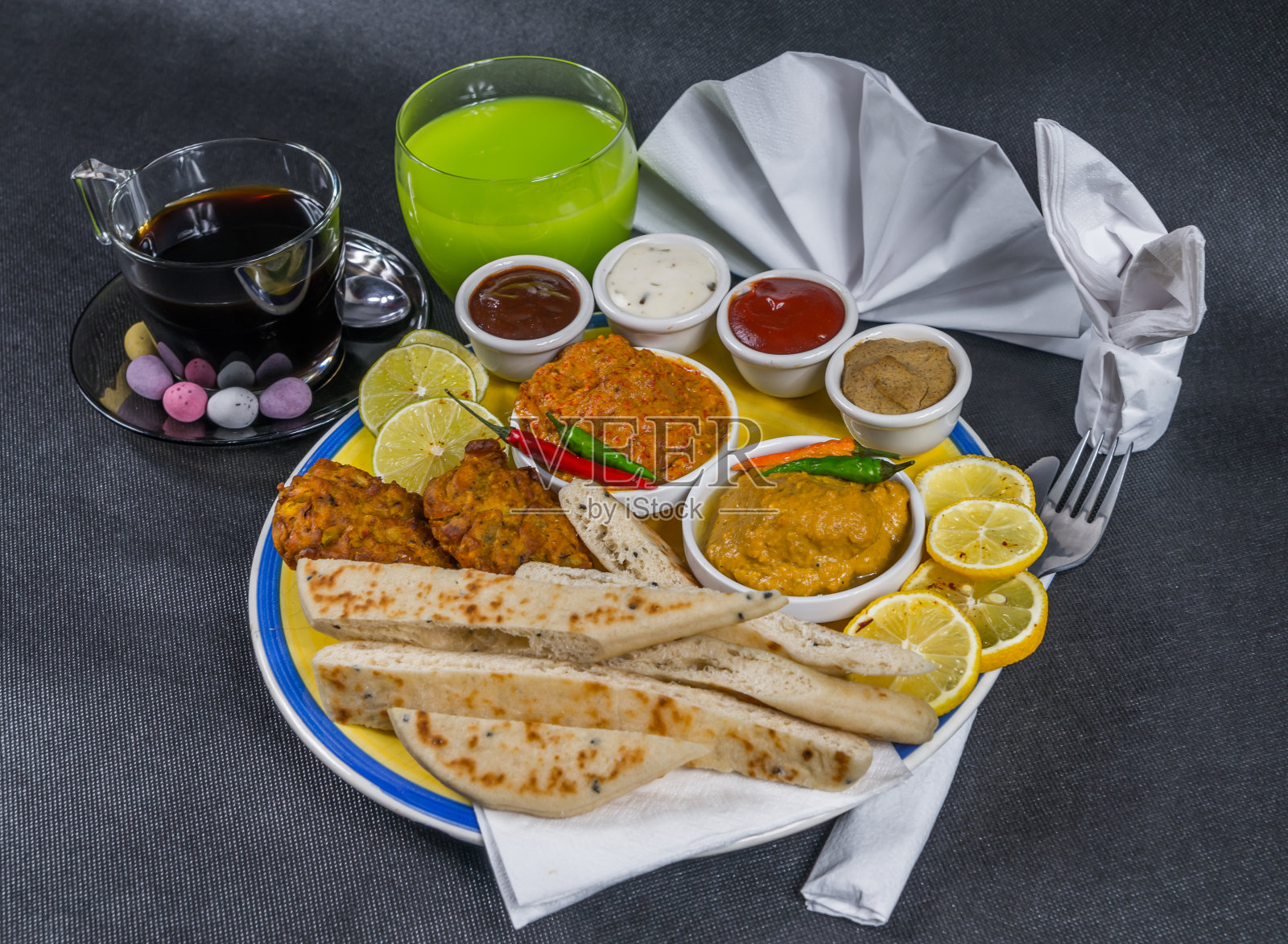 东方印度套餐，咖喱鸡，咖喱鸡，印度烤饼，洋葱巴吉，盘子，咖啡，绿色饮料，餐巾，辣椒照片摄影图片