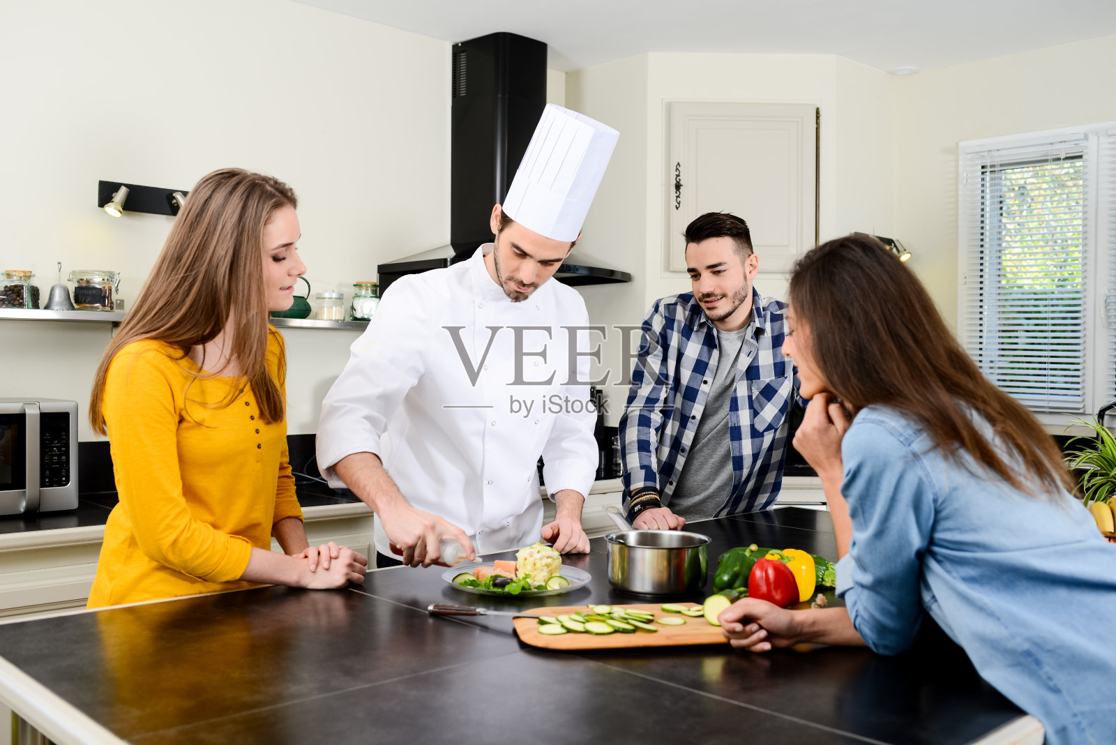 专业的私人厨师在客户的私人厨房里做饭，给年轻人在家里上烹饪课照片摄影图片
