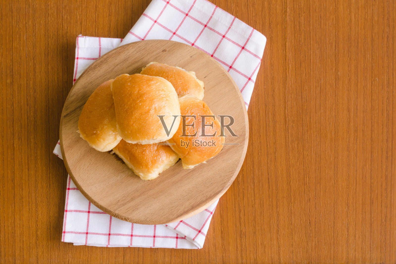 新鲜的自制烘焙美味的黄油面包面包在木制托盘上，红白餐巾纸在棕色柚木地板背景与阳光在一边快乐的早餐与复印空间在右边照片摄影图片