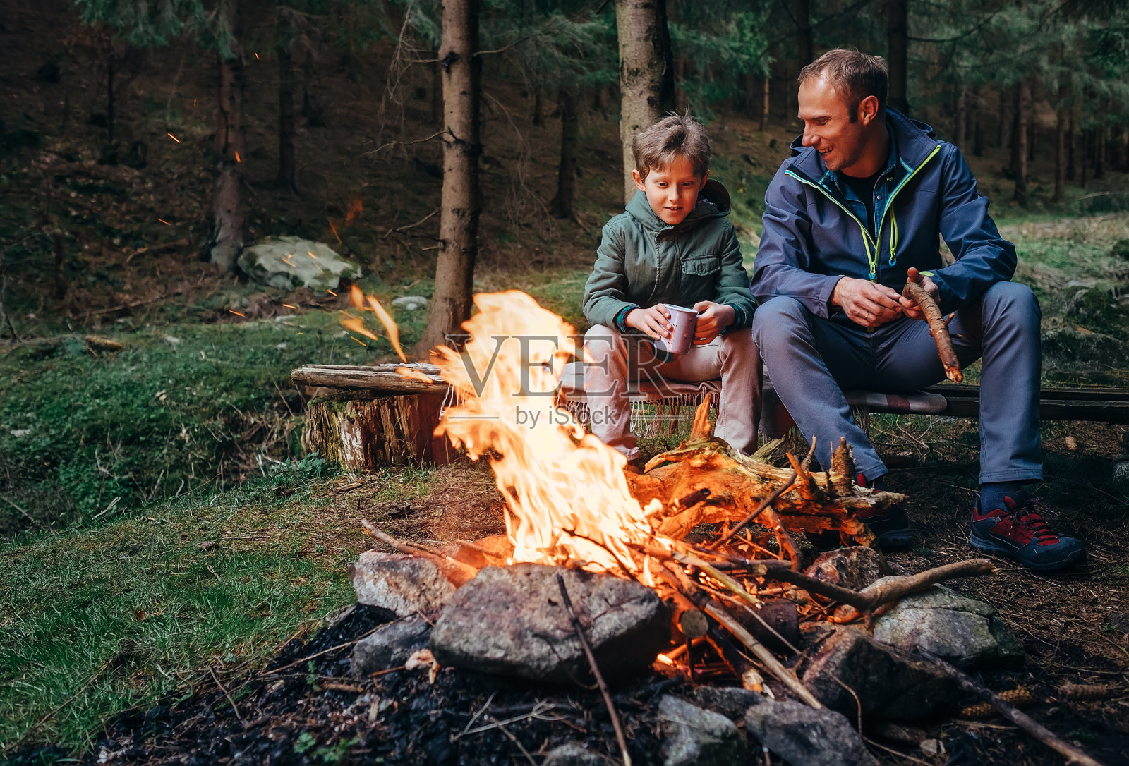 父亲和儿子在篝火旁取暖，喝茶聊天照片摄影图片
