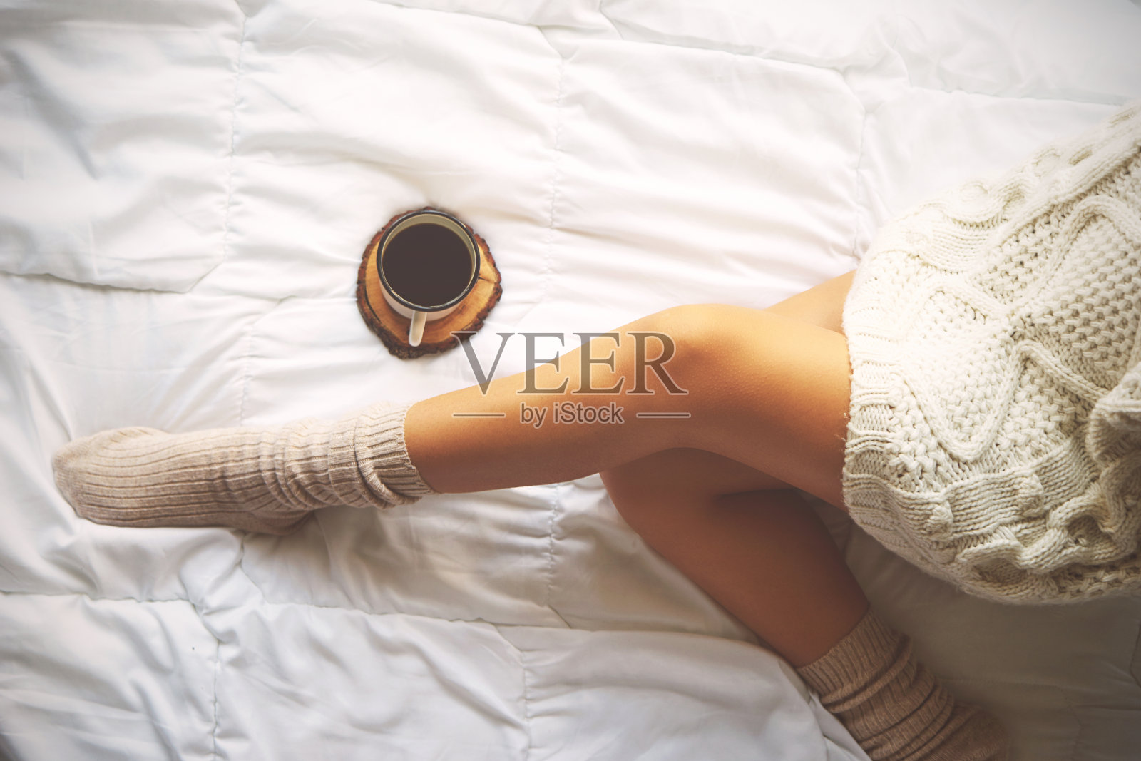 软照片的女人在床上与一杯咖啡，顶部的观点照片摄影图片