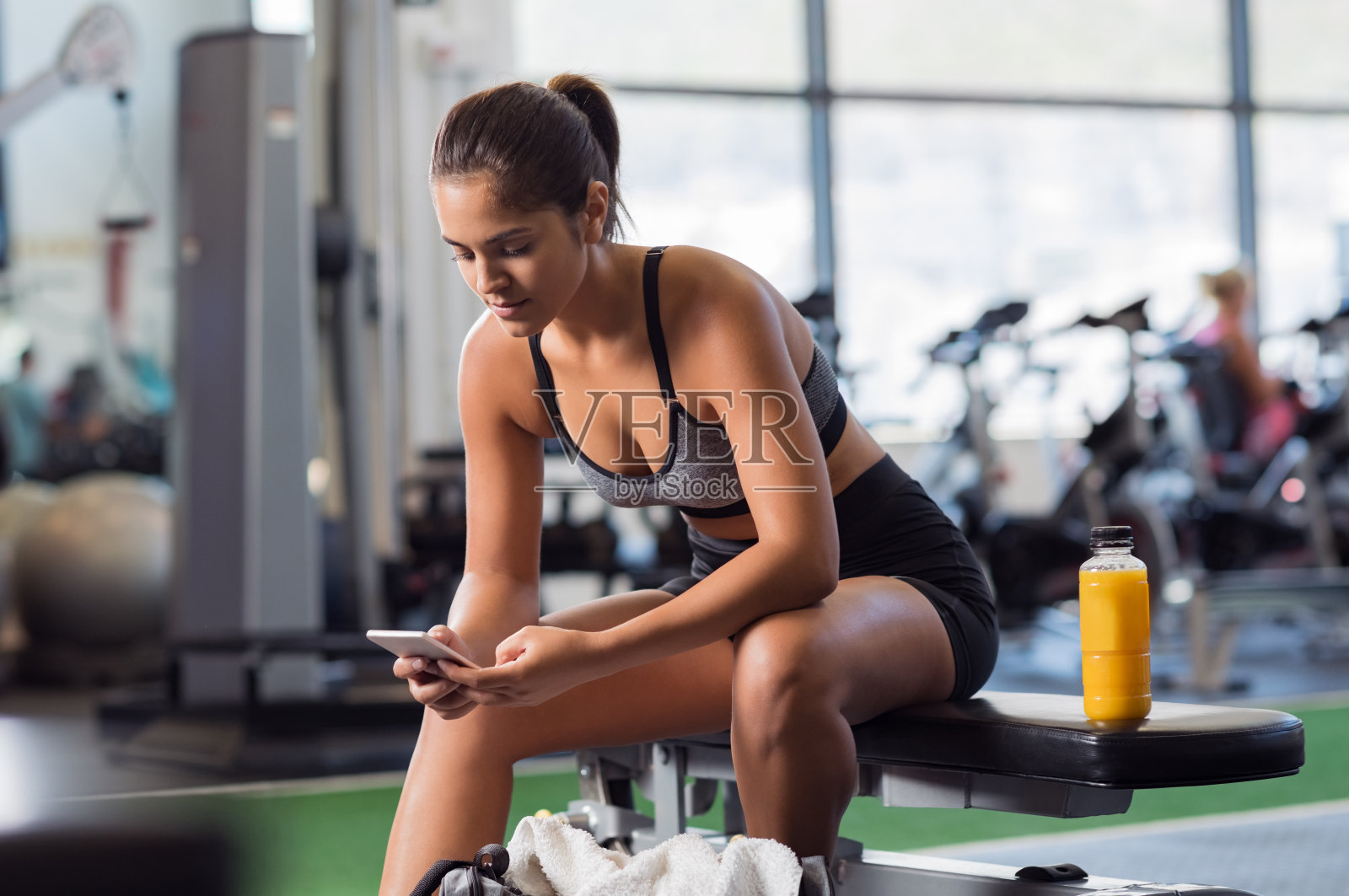 在健身房用手机的女人照片摄影图片