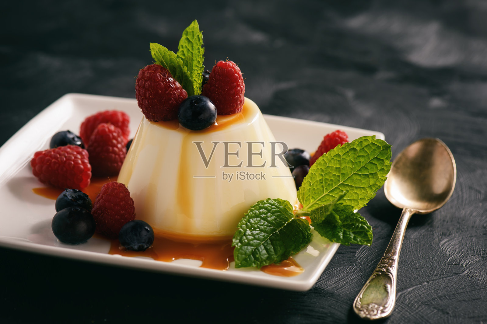 意大利甜点-意式奶冻配浆果和焦糖酱。照片摄影图片