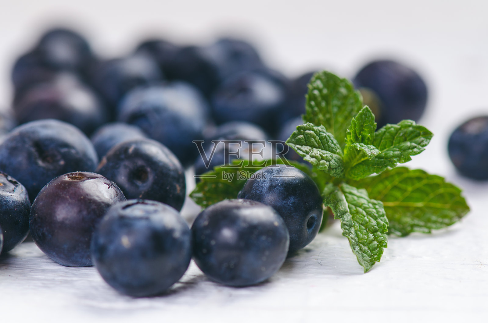 白色木制桌子上放着新鲜的蓝莓和薄荷。天然抗氧化剂。健康食品的概念。有机的超级食物照片摄影图片