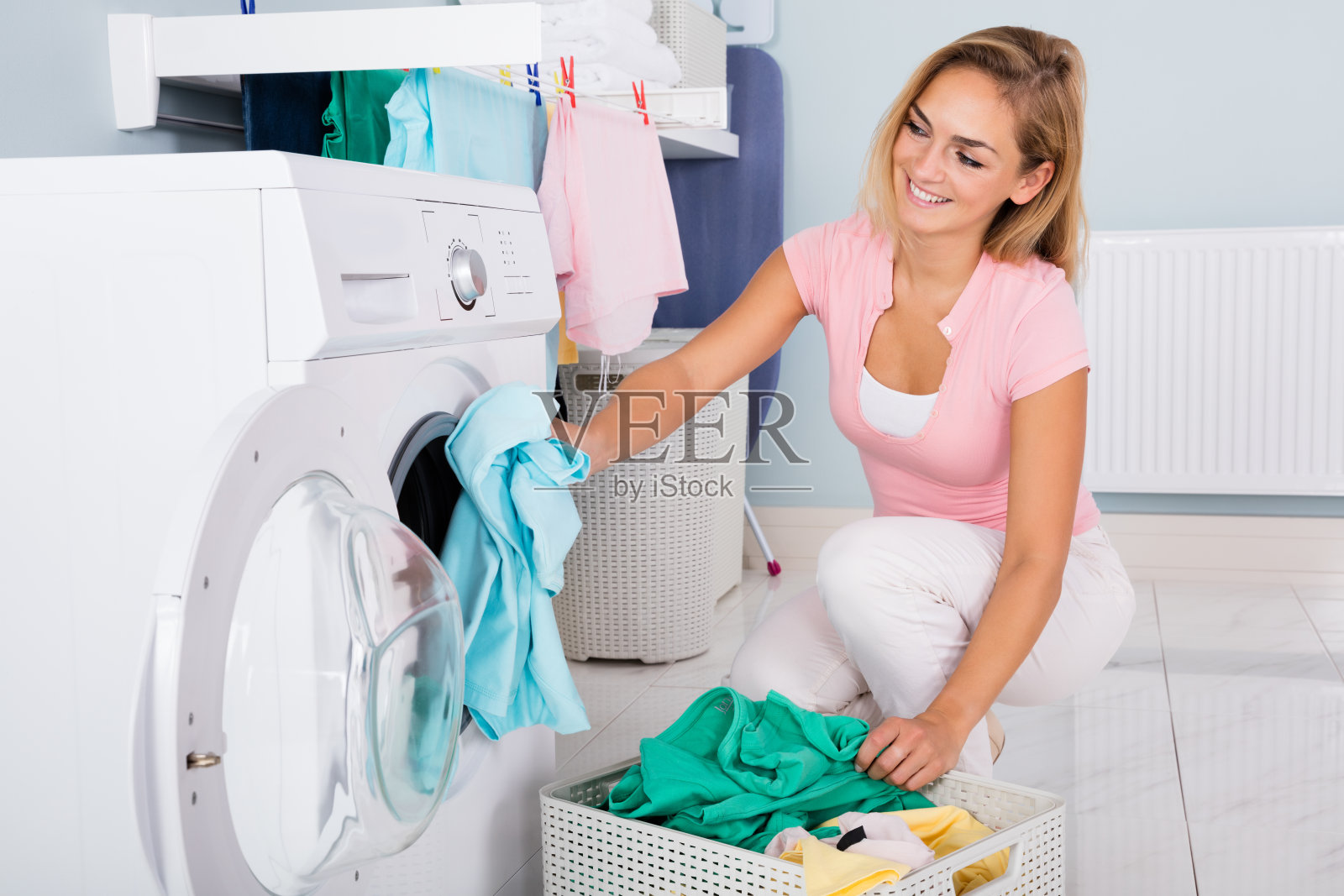 微笑的女人把衣服放进洗衣机照片摄影图片