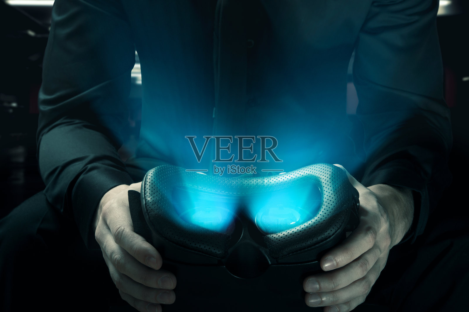 虚拟现实的黑暗面。男人拿着发光的VR眼镜照片摄影图片