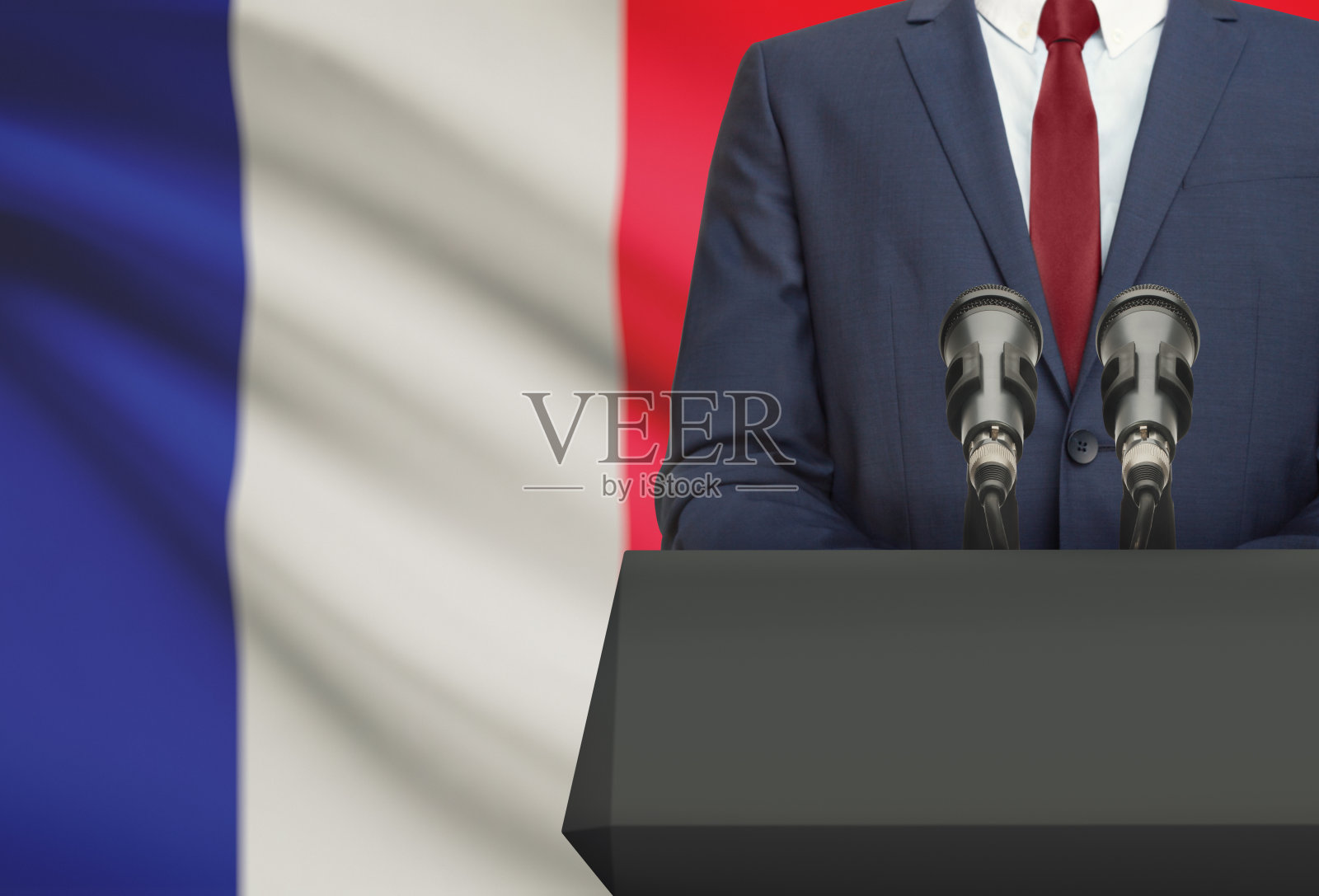 商人或政治家在讲坛后面发表演讲，背景是法国国旗照片摄影图片