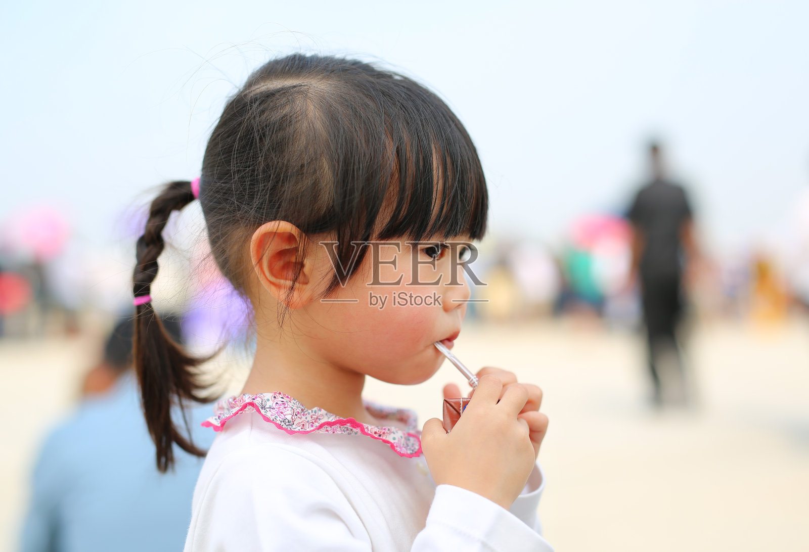 小女孩用吸管喝牛奶的特写。肖像户外。照片摄影图片