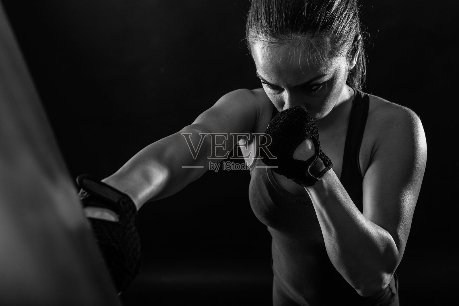 摄影棚拍摄的女拳击手打拳击袋。照片摄影图片