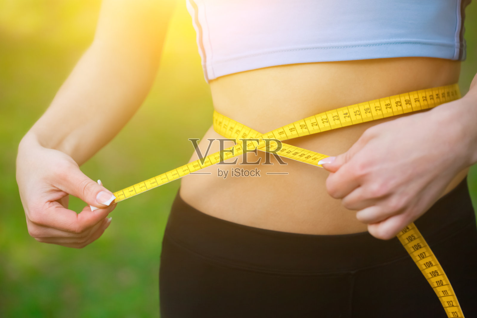 运动女孩用黄色的卷尺测量腰围。减少多余的重量照片摄影图片