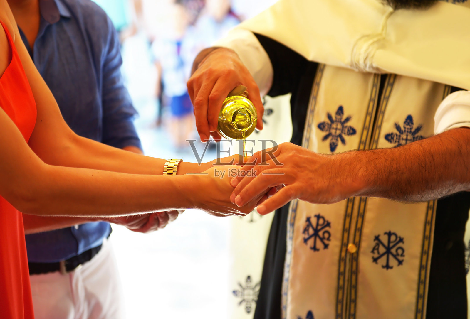 神父将洗礼油涂在教母希腊的手上照片摄影图片