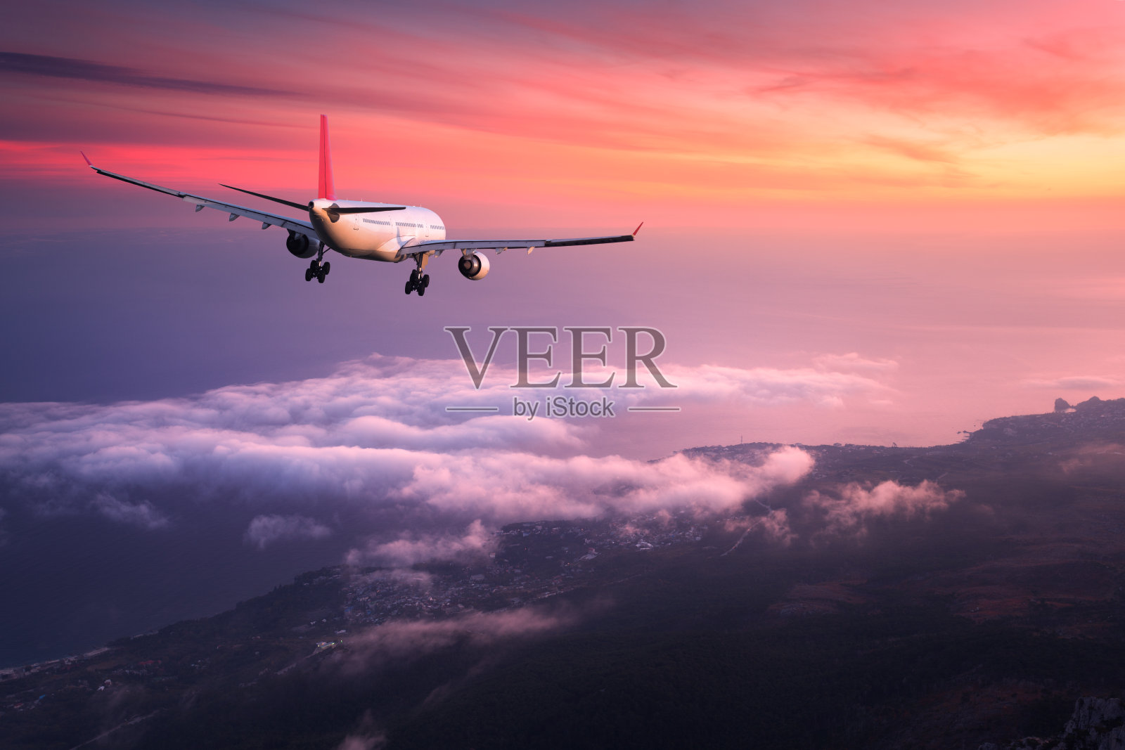 飞机。风景与巨大的白色客机是飞行在红色的天空之上的云彩在彩色日落。的旅程。客机在黄昏时分降落。商务旅行。商用飞机照片摄影图片