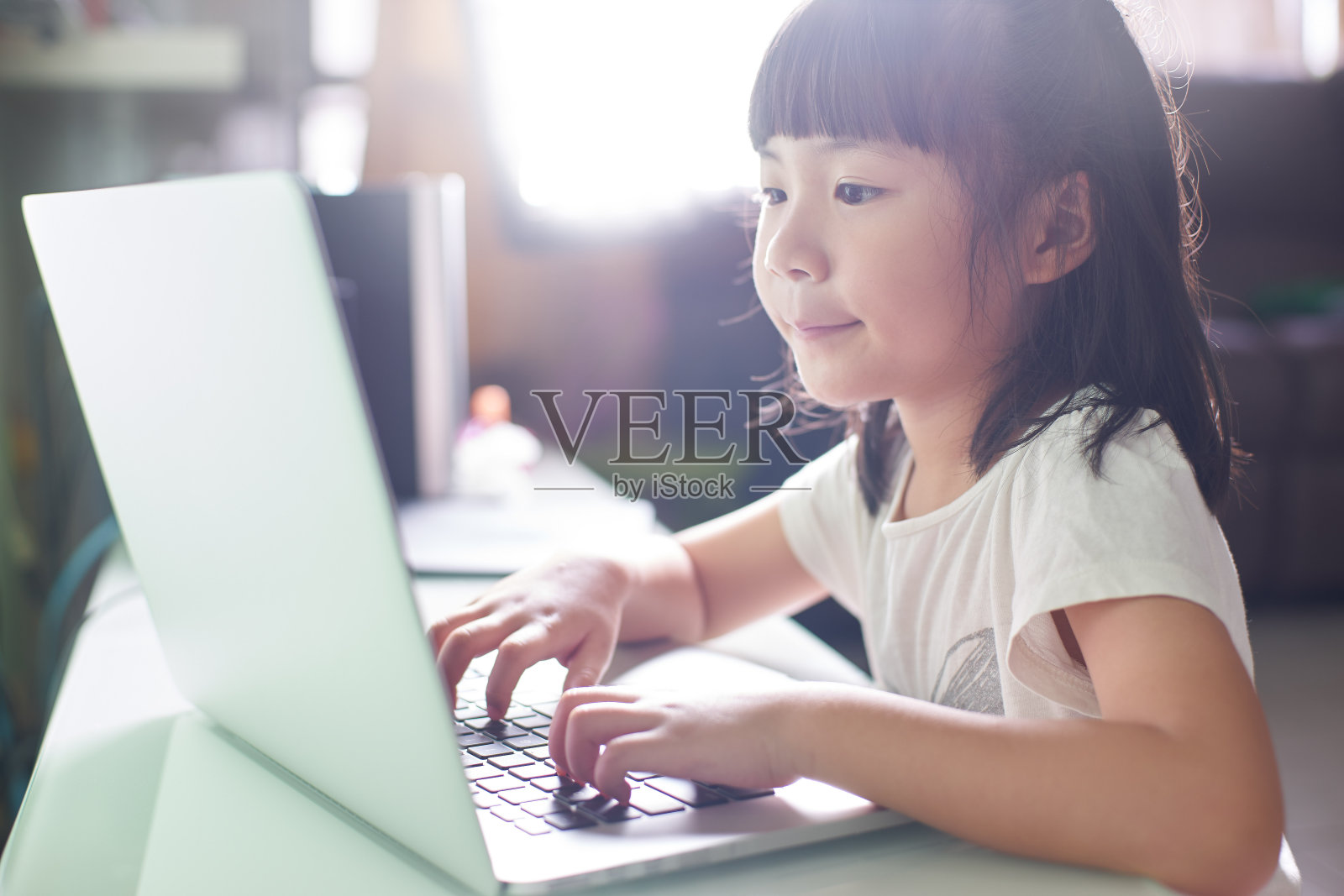 亚洲小女孩用手提电脑学习。选定焦点为背景模糊的眼睛。照片摄影图片