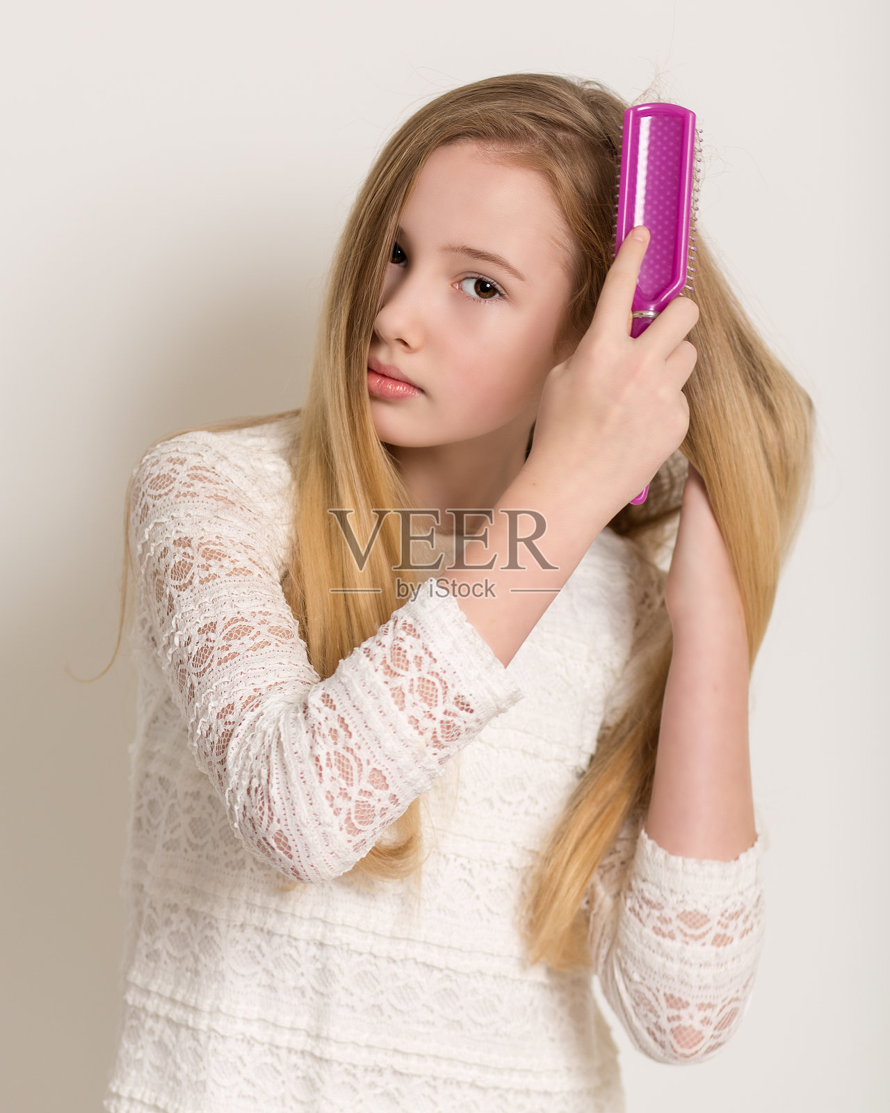 漂亮年轻的金发女孩梳着她的头发照片摄影图片