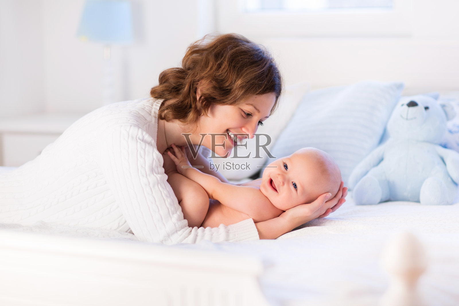 妈妈和婴儿在白色的床上照片摄影图片