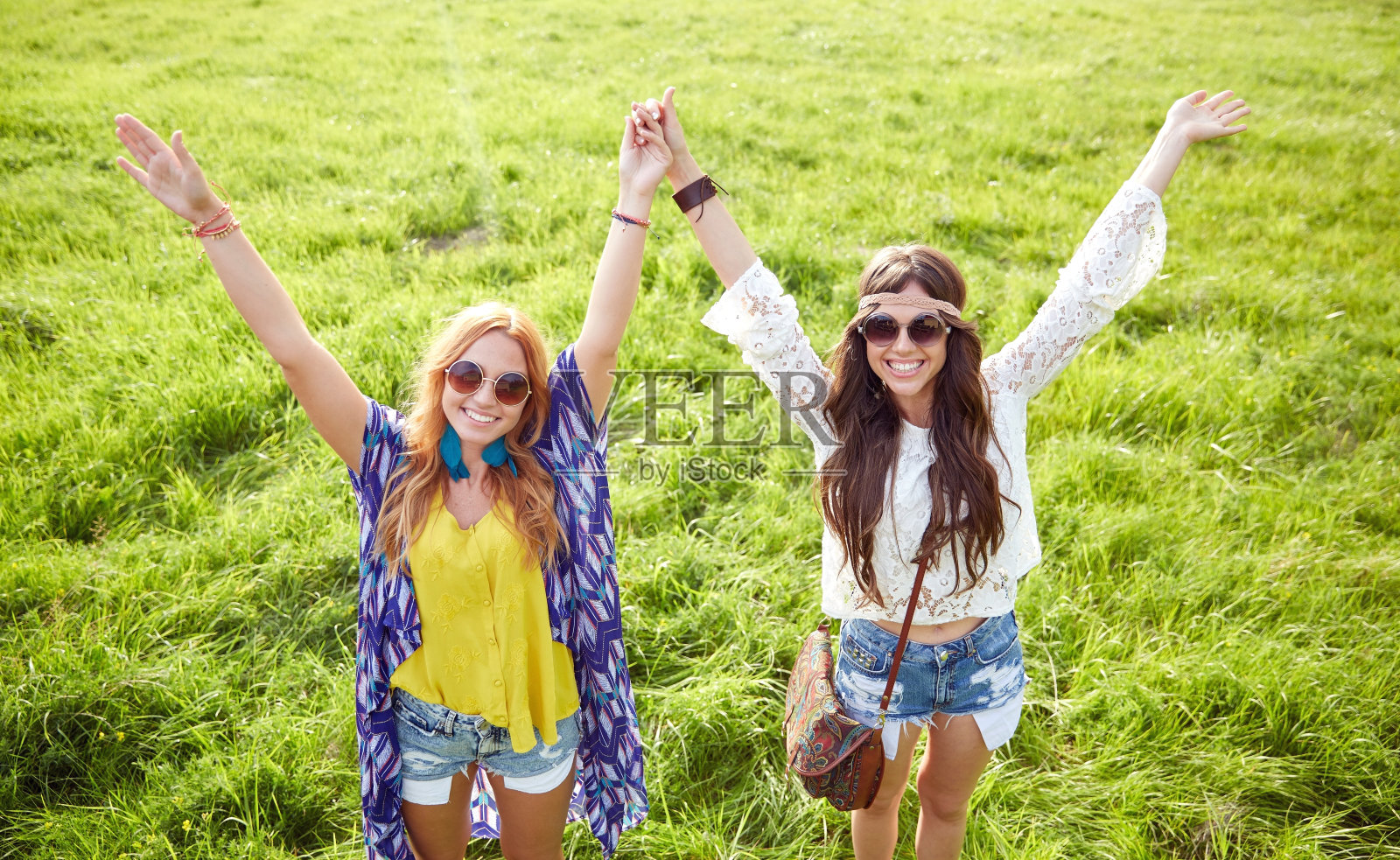 年轻的嬉皮女人微笑着在绿色的田野上跳舞照片摄影图片