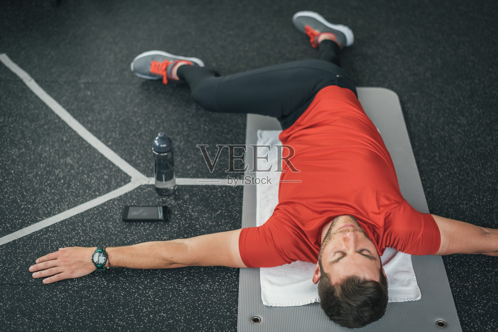 在健身房室内的垫子上锻炼前，运动员伸展照片摄影图片