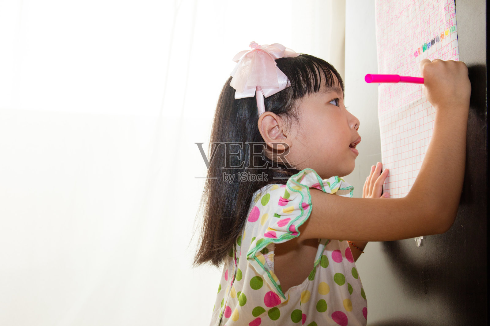 亚洲华人小女孩用背光在纸上写字照片摄影图片
