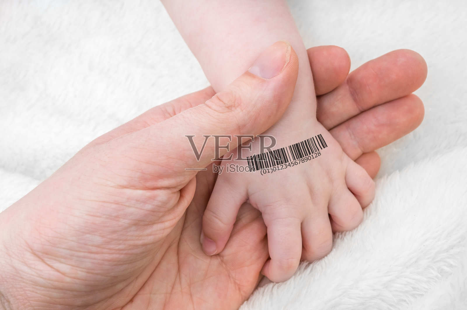 一个男人牵着一个婴儿的手，上面有条形码。基因克隆的概念。照片摄影图片