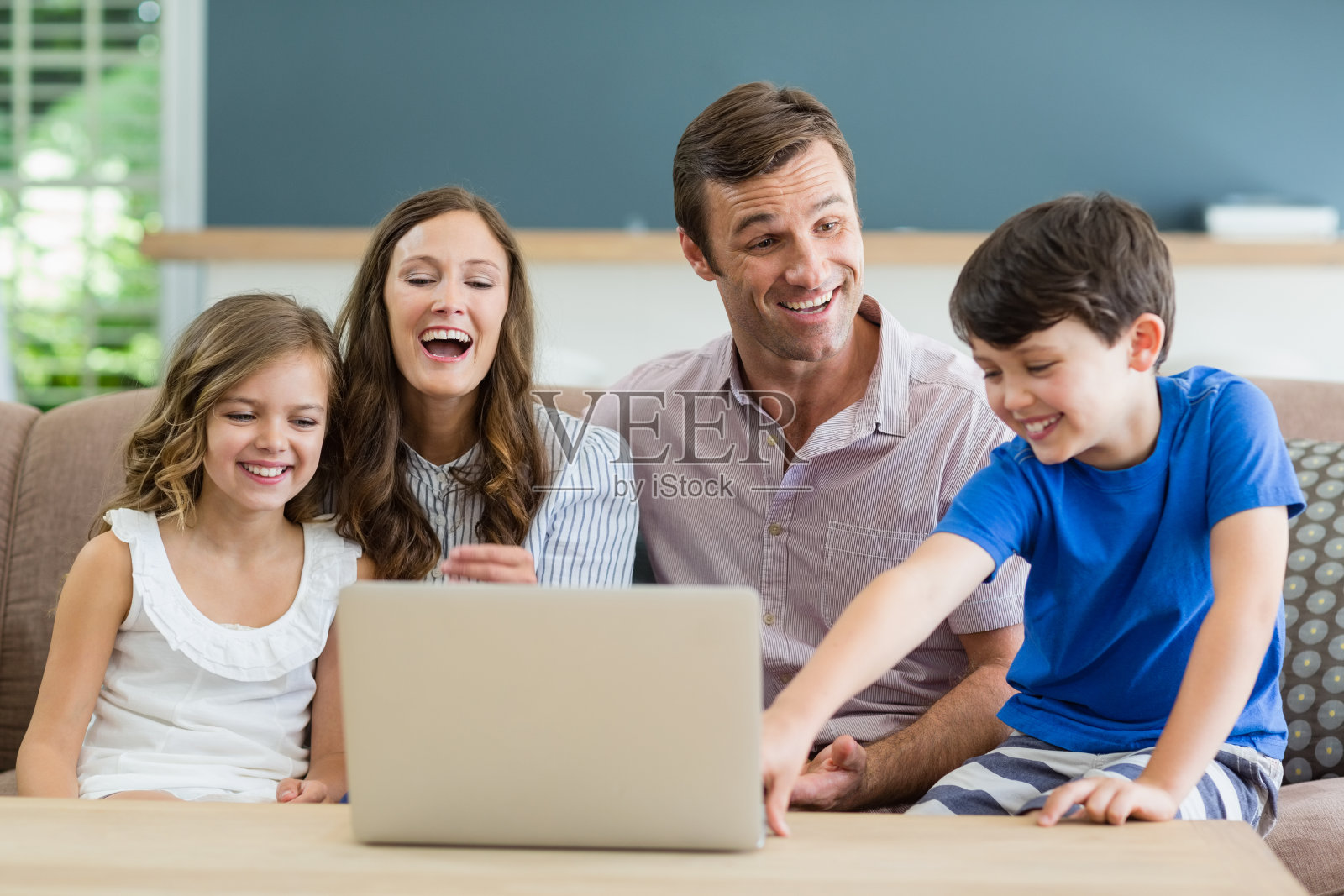 家人坐在沙发上使用笔记本电脑在家里的客厅照片摄影图片