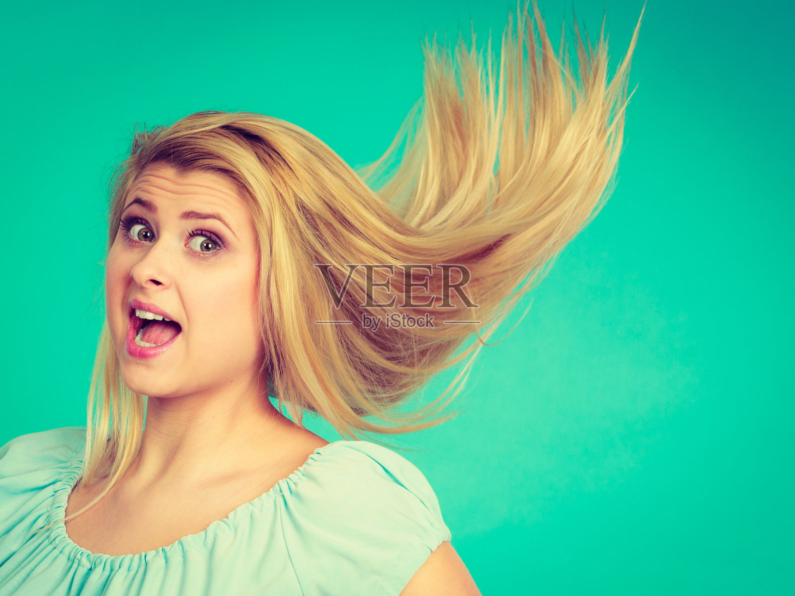 震惊的金发女人与疯狂的风吹头发照片摄影图片