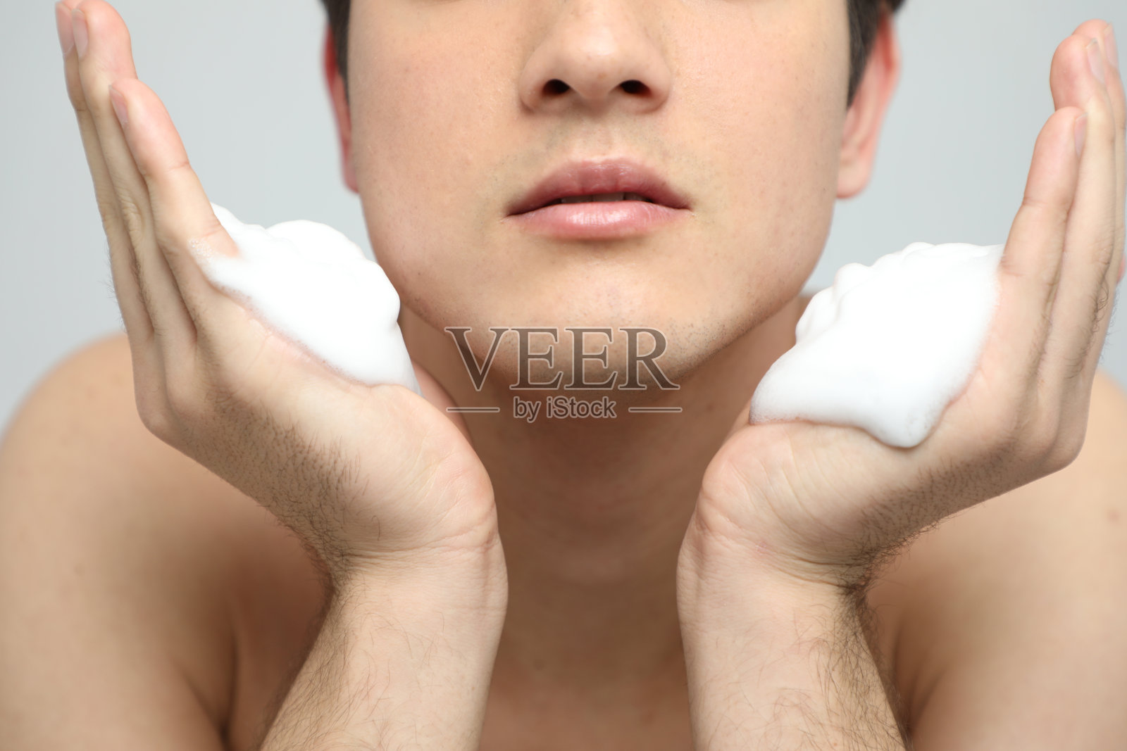 年轻人用洁面泡沫洗脸，男士护肤理念，治疗青春痘照片摄影图片